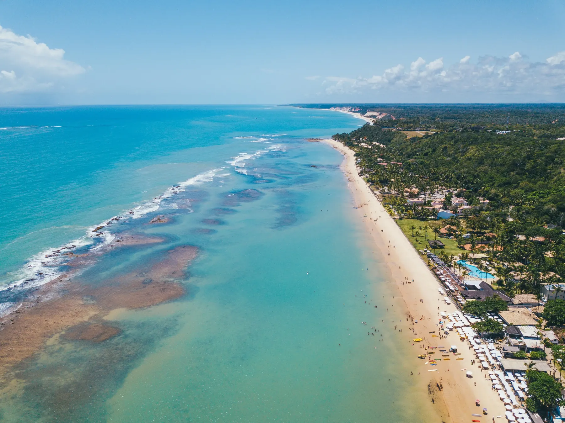 Vista aérea do litoral de Arraial d'Ajuda, com praia, mar e recifes