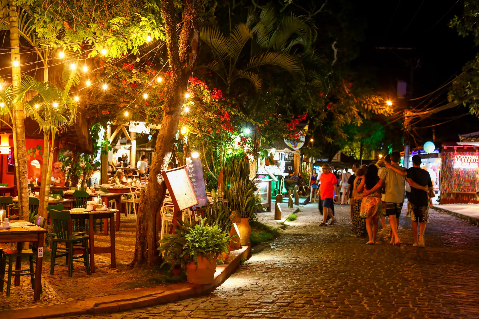 Restaurantes e luzes na Rua do Mucugê à noite em Arraial d'Ajuda