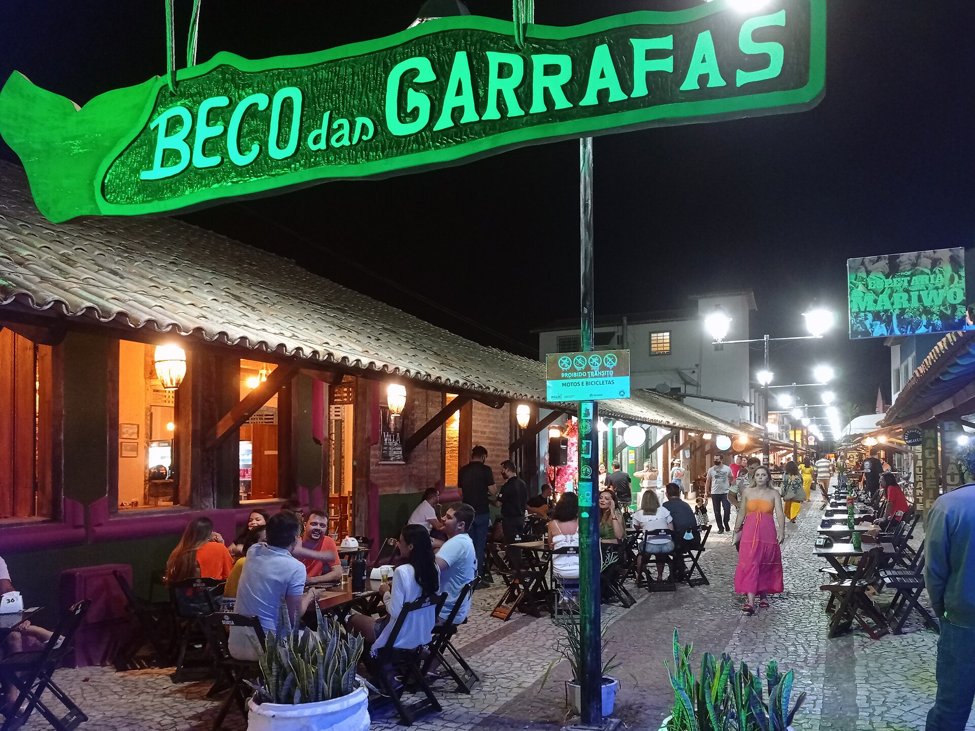 Restaurantes e visitantes no Beco das Garrafas à noite em Prado