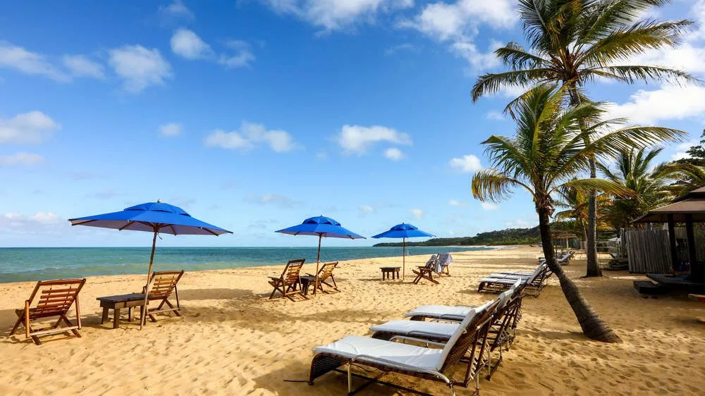 Cadeiras e guarda-sóis azuis na areia da Praia do Rio Verde em Trancoso