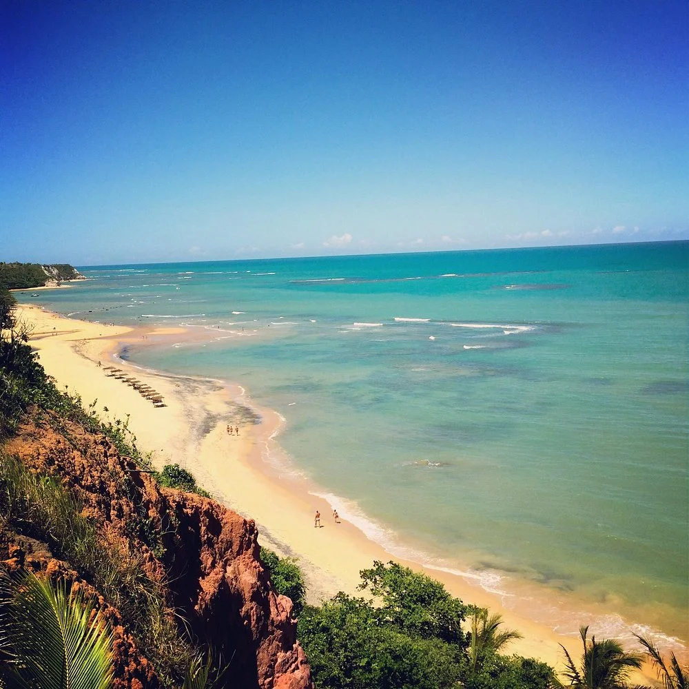 Vista elevada da Praia do Espelho com mar azul e falésias